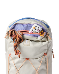 Light colored daypack with open main compartment showing interior organization and decorative items