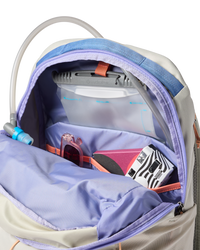 Light colored backpack opened showing interior compartments with laptop sleeve and organized pockets