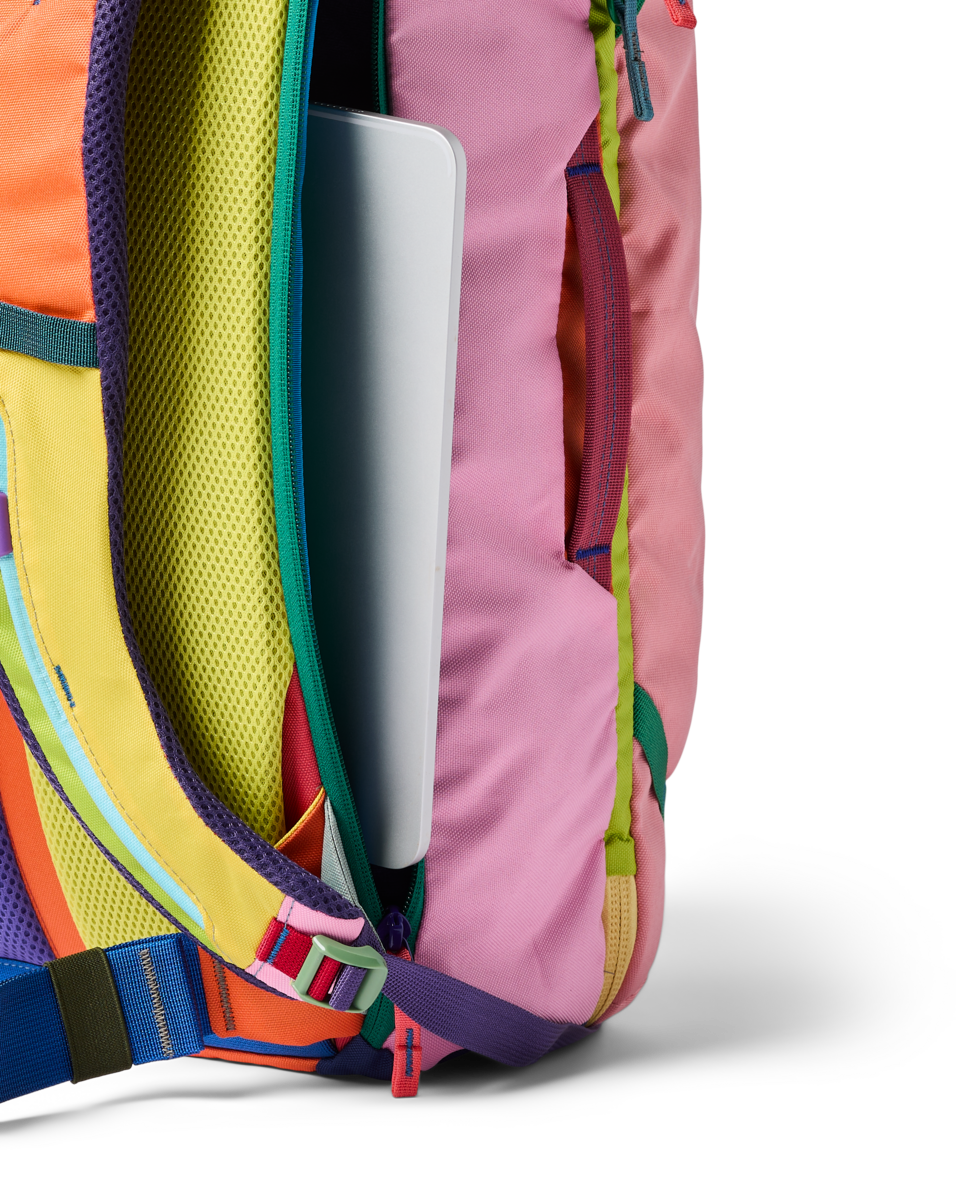 Multicolored travel backpack with laptop compartment open, showing vibrant patchwork design