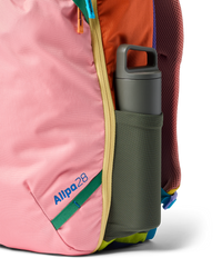 Multicolored travel backpack with water bottle in side pocket, showing various bright fabric panels