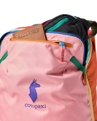 Multicolored travel backpack with passport holder visible, showing pink main panel and rainbow accent panels