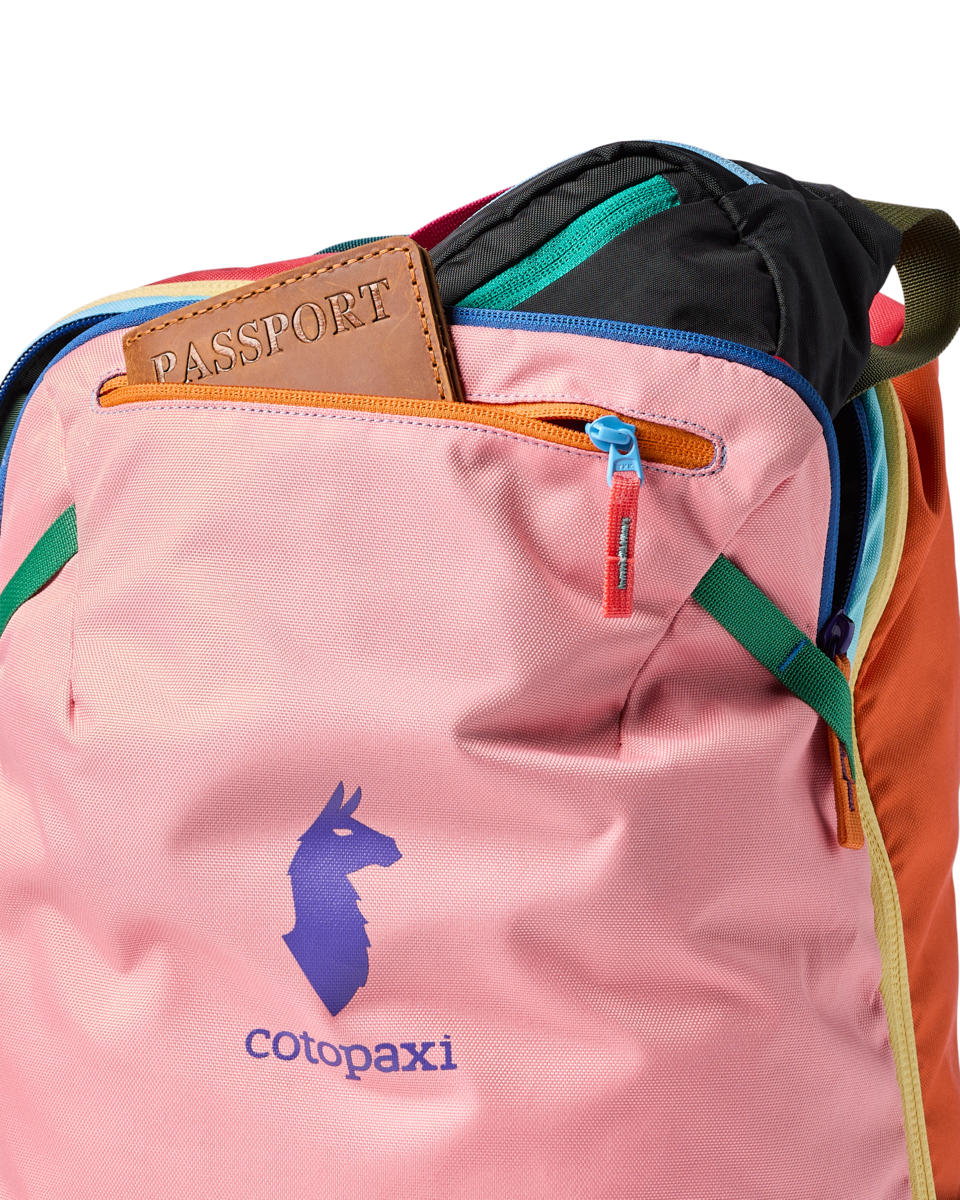 Multicolored travel backpack with passport holder visible, showing pink main panel and rainbow accent panels