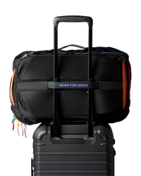 Black travel backpack with colorful zipper accents attached to rolling luggage handle
