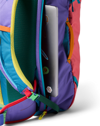 Multicolored travel backpack with laptop compartment open showing silver laptop inside