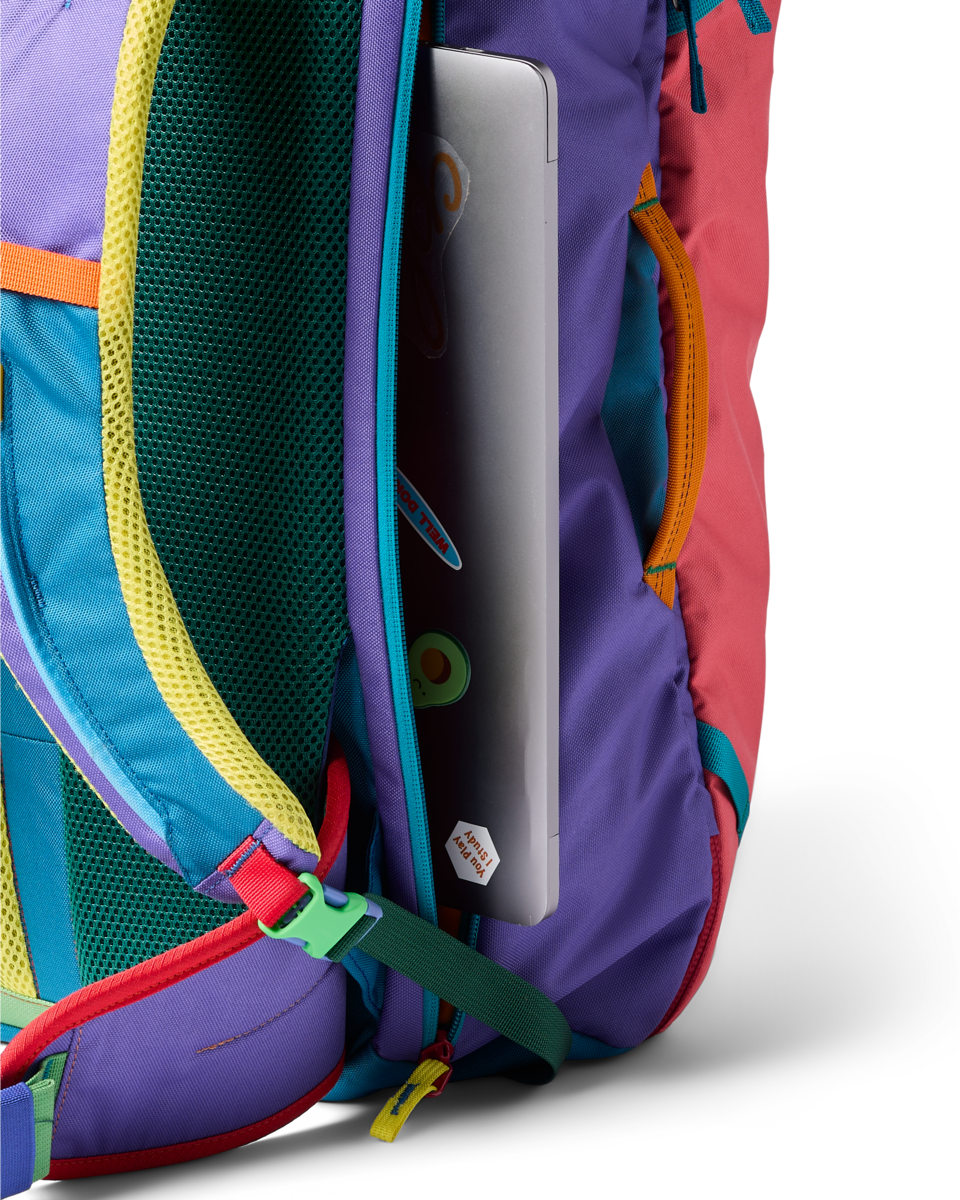 Multicolored travel backpack with laptop compartment open showing silver laptop inside