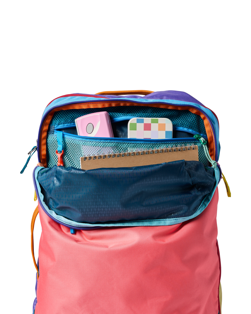 Multicolored travel backpack with main compartment open showing organized interior pockets and storage