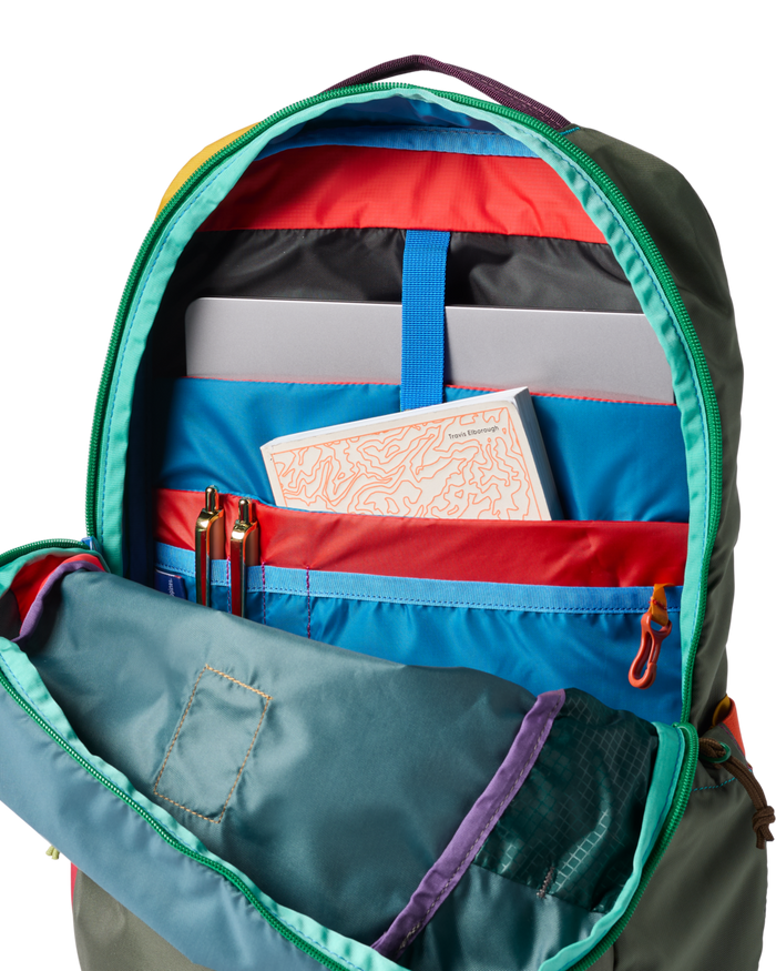 Open backpack interior detail showing multiple compartments, laptop sleeve, pens, and a book