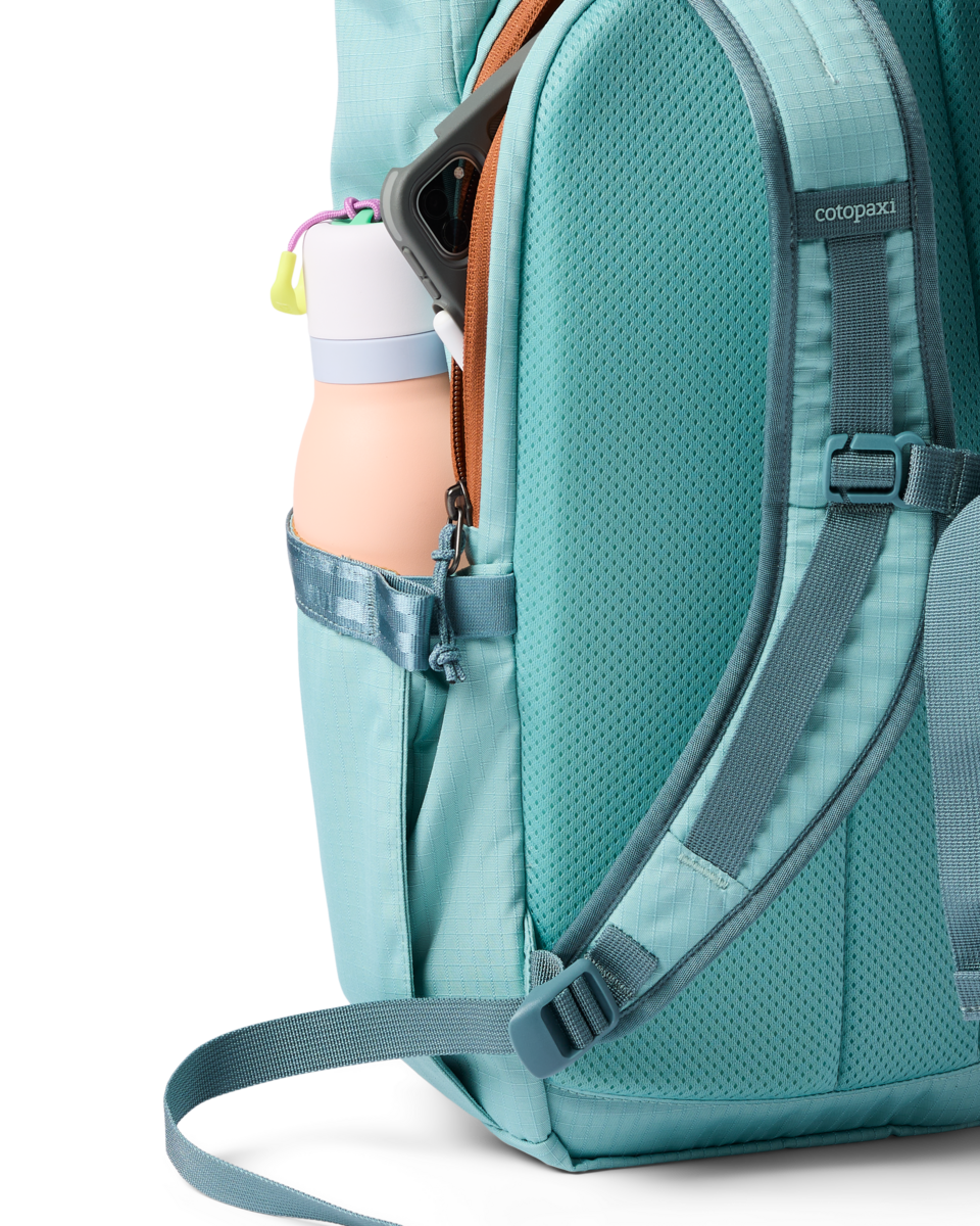 Teal daypack side view showing water bottle pocket, shoulder straps, and open main compartment