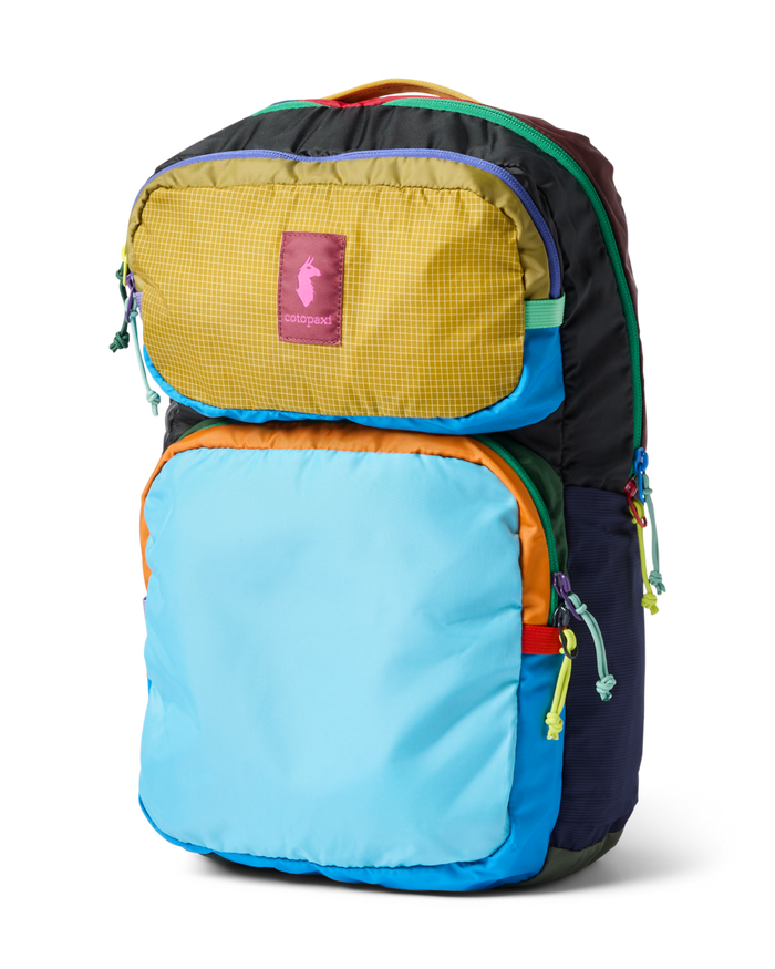 Colorful patchwork backpack with multiple compartments and rainbow zipper pulls, three-quarter view
