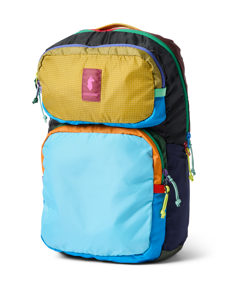 Colorful patchwork backpack with multiple compartments and rainbow zipper pulls, three-quarter view