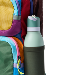 Colorful patchwork backpack with water bottle in side pocket, close-up detail view