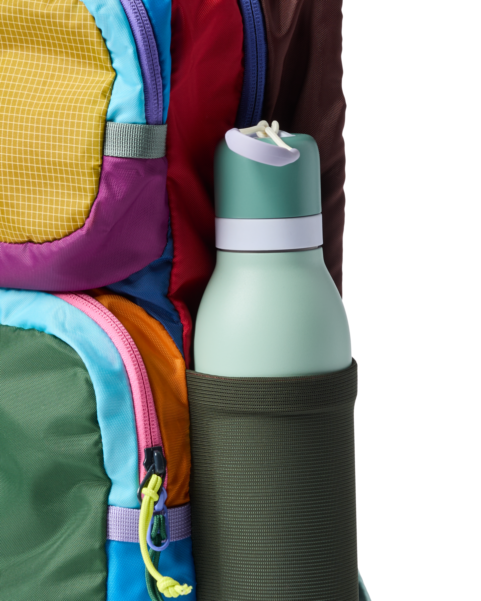 Colorful patchwork backpack with water bottle in side pocket, close-up detail view
