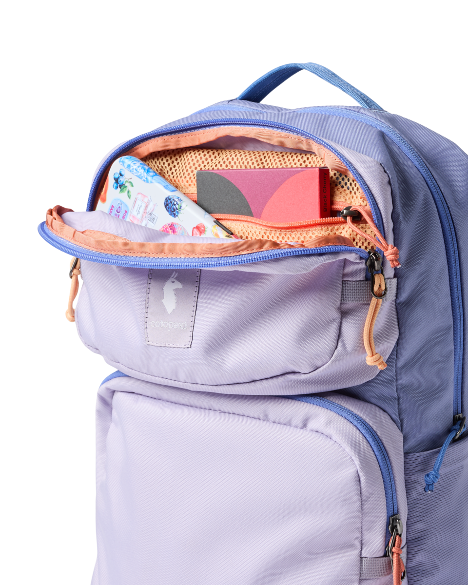 Light purple backpack with open main compartment showing orange interior and organized contents