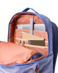 Open backpack showing interior compartments with coral lining and organizational pockets containing notebook and supplies