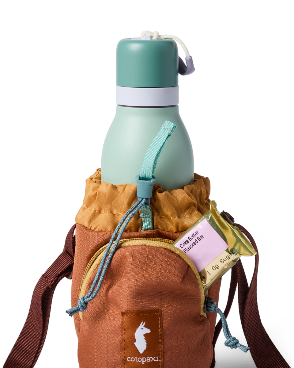 Water bottle sling bag holding a mint green insulated bottle with snack bar in side pocket