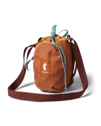Small cylindrical drawstring crossbody sling bag with ripstop fabric, teal cord pulls, and burgundy shoulder strap