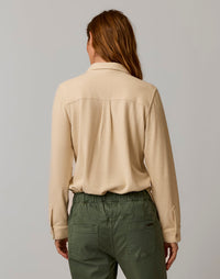 Women's long-sleeve button-up shirt in light beige, back view, with collar and cuffed sleeves