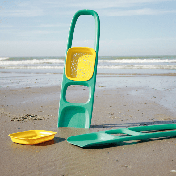 Teal beach sand toy with yellow bucket attachment and matching accessories on sandy shore