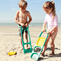Children using teal and yellow sand scooping tool on beach
