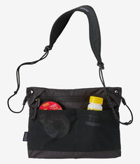 Black crossbody bag with adjustable shoulder strap and front mesh pockets containing items