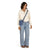 Small crossbody bag in muted blue worn crossbody over cream pullover, front on-model view