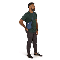 Man wearing a small blue crossbody bag with shoulder strap, front angle view