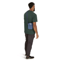 Small blue crossbody bag worn diagonally across back of male model, back view