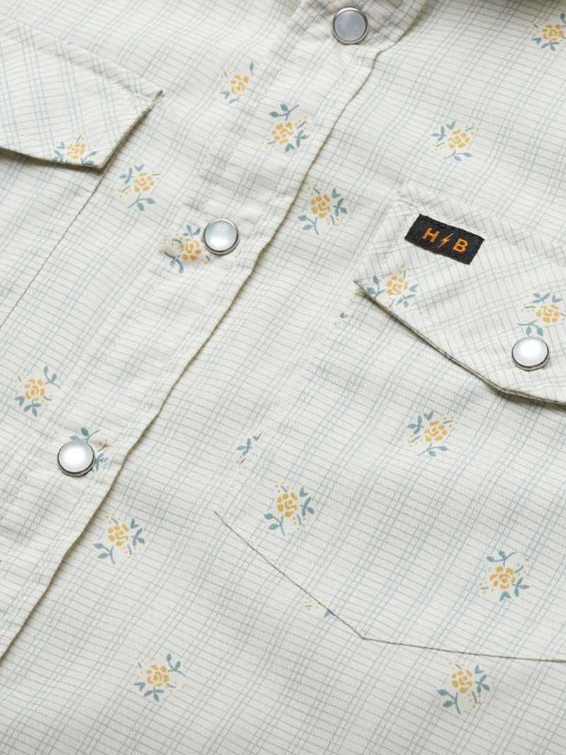 Close-up detail of western snap shirt with floral grid pattern, chest pockets, and silver snaps