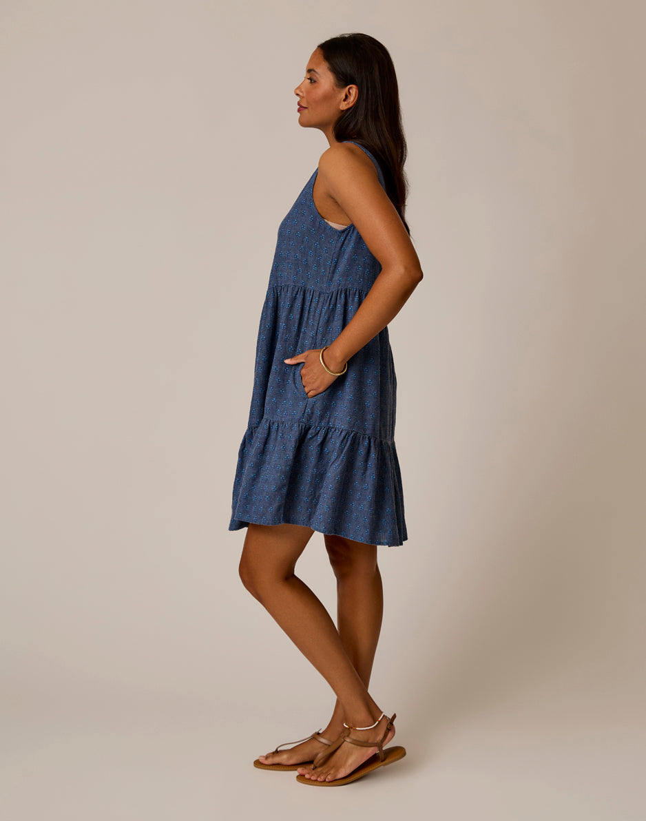 Blue sleeveless tiered dress with small white dot pattern, side view on model