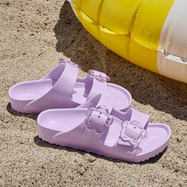 Light purple EVA sandals with two adjustable buckle straps on sandy beach surface