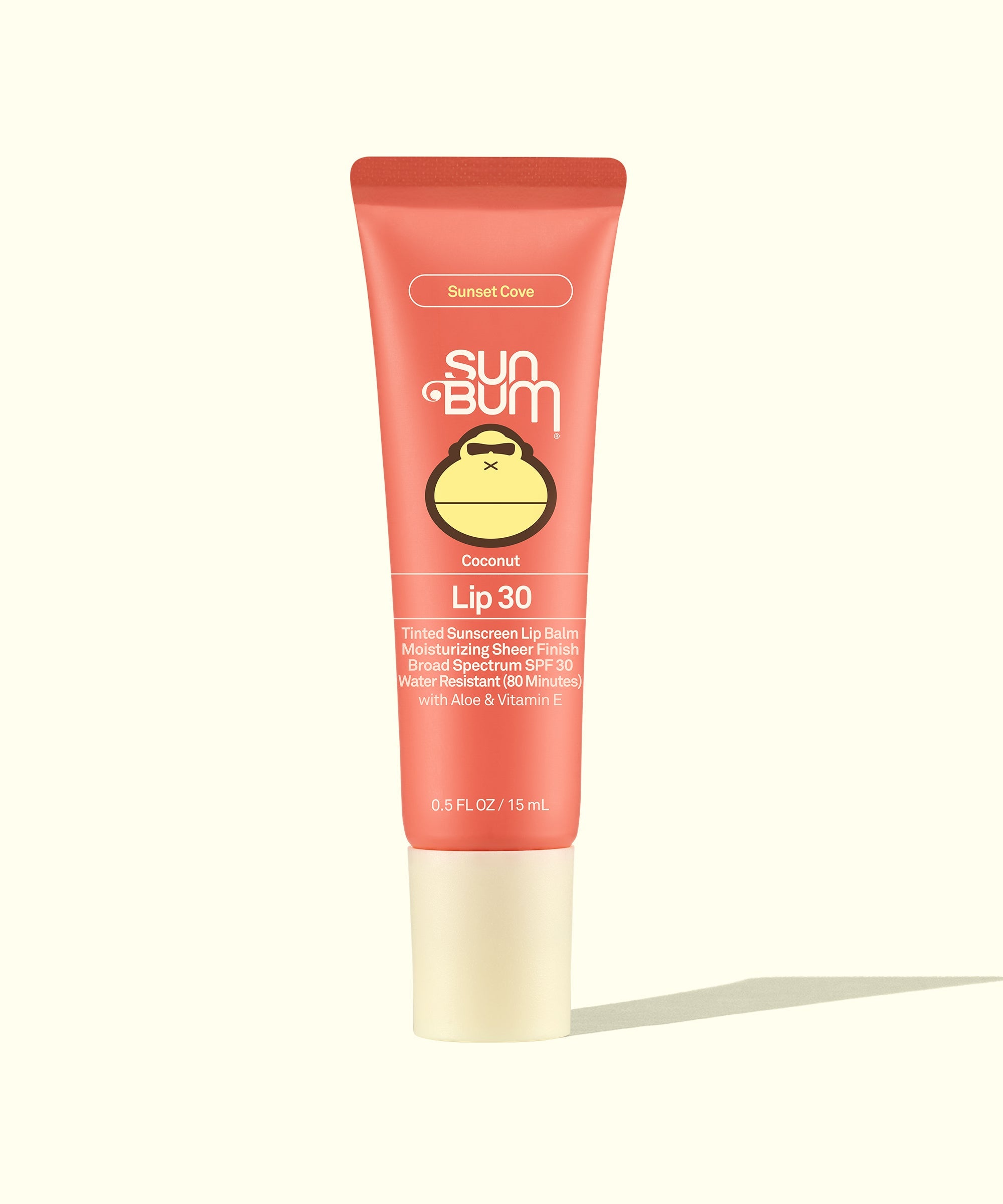 Coral pink tinted lip balm tube with SPF 30 protection, standing upright against cream background