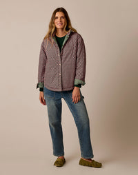 Women's reversible checker-print jacket with green lining, worn open over jeans, front view