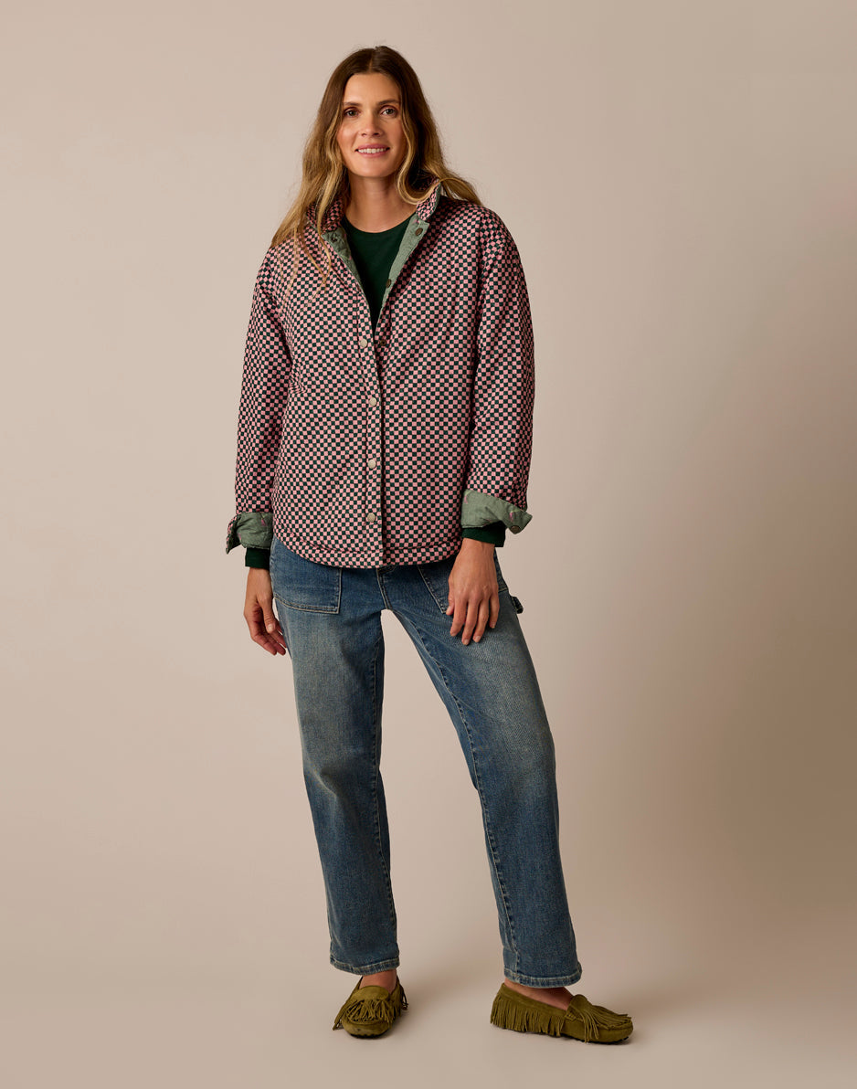 Women's reversible checker-print jacket with green lining, worn open over jeans, front view