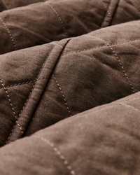 Close-up detail of diamond quilted stitching on a dark brown fabric jacket