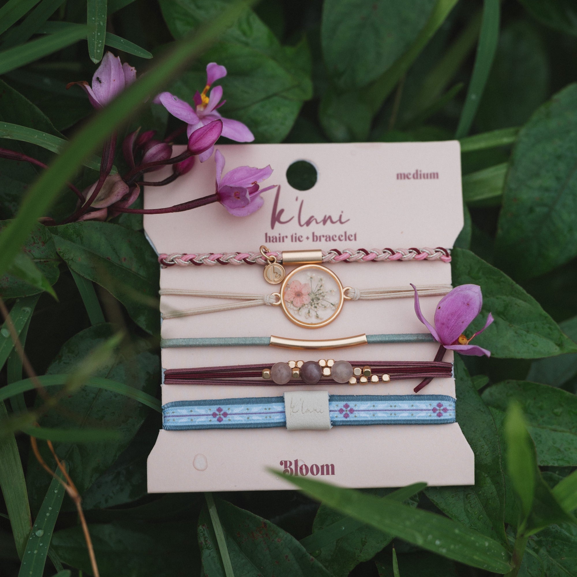 Set of five hair ties and bracelets with floral charm, braided, beaded, and patterned elastic bands on display card
