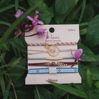 Set of five hair ties and bracelets with floral charm, braided, beaded, and patterned elastic bands on display card