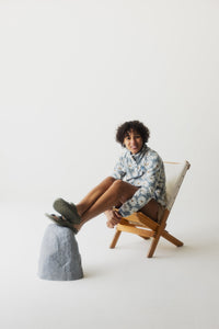 Light blue button-up shirt with white daisy print worn by seated woman