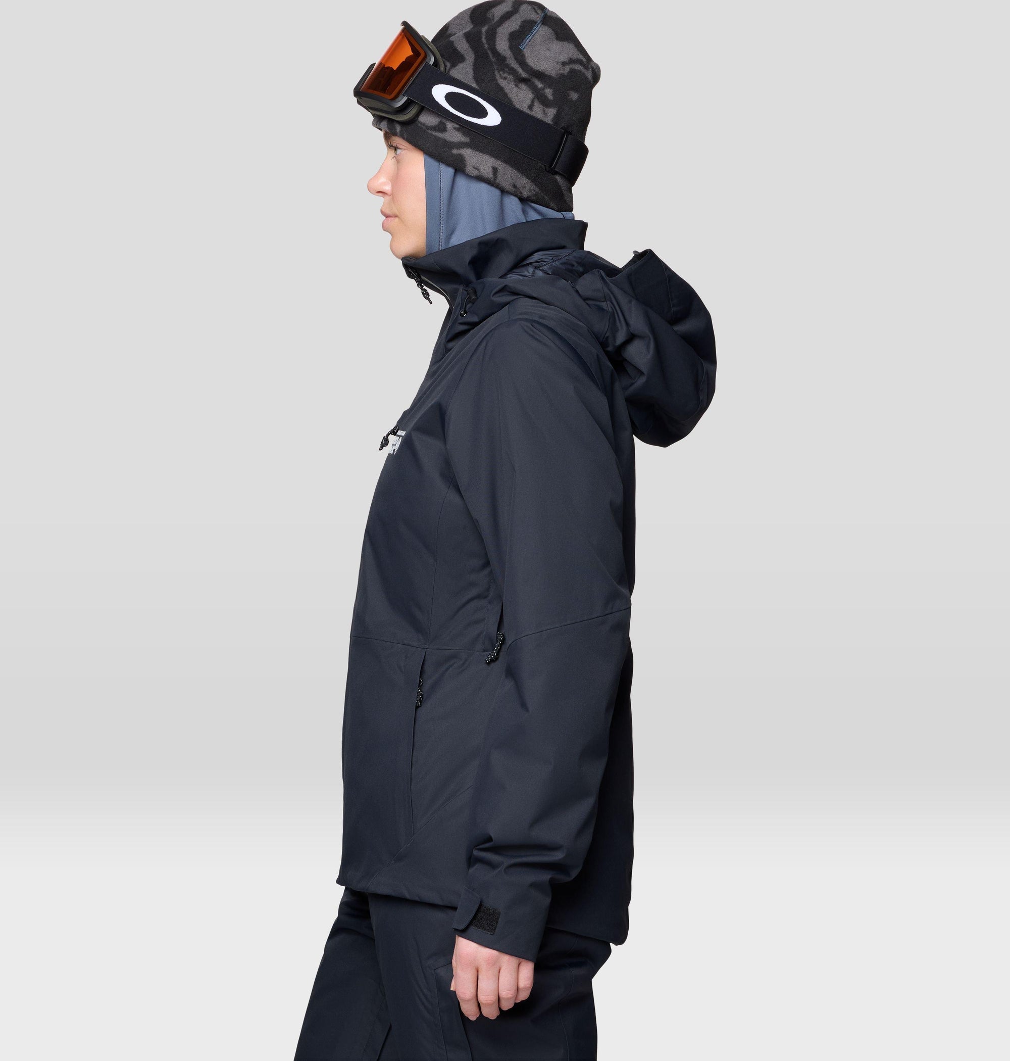 Women's insulated ski jacket in black, side profile view with hood and goggles