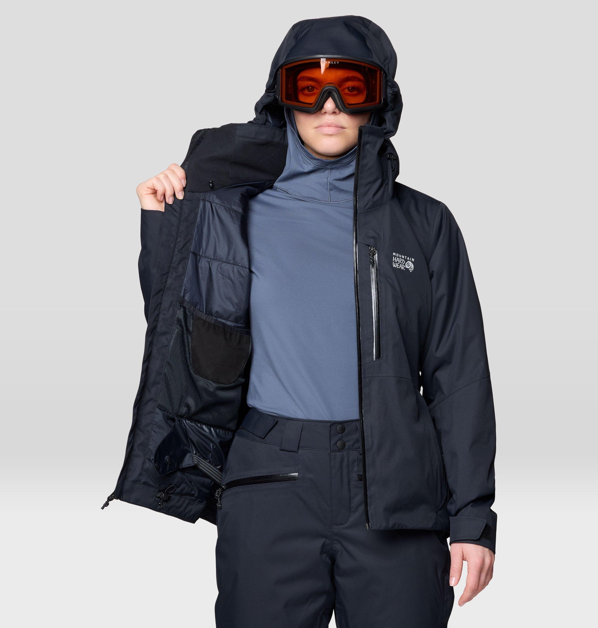 Women's insulated ski jacket in black, open to show interior lining, worn with goggles