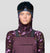 Women's ski bib overalls in plum purple with shoulder straps, worn with camo base layer and goggles