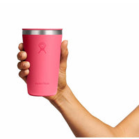 Hand holding a bright pink insulated tumbler cup with stainless steel rim, front view