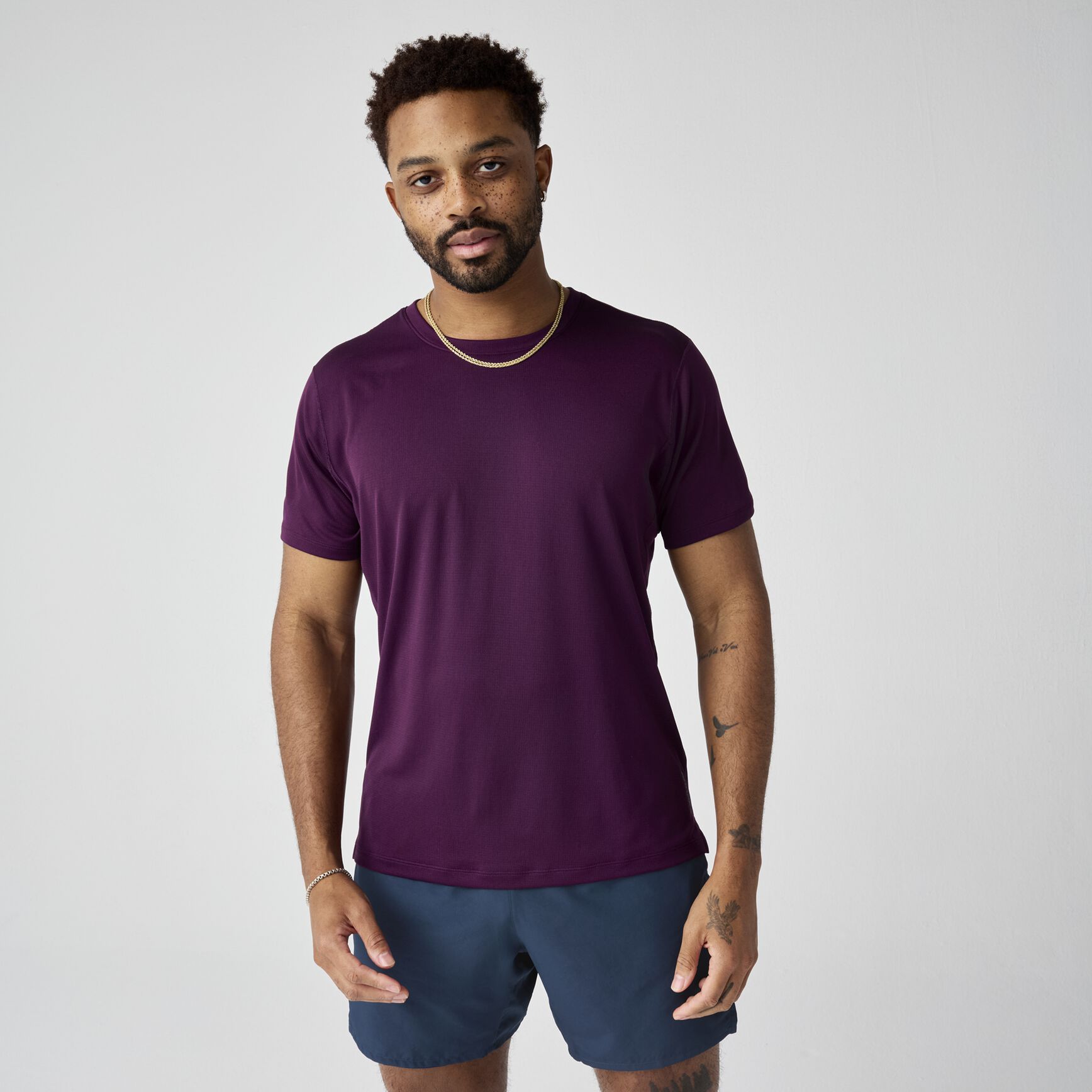 Man wearing deep purple short sleeve athletic t-shirt with blue shorts