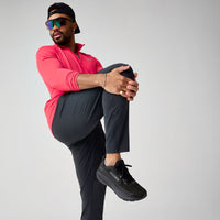 Man wearing black athletic running pants in active pose with knee raised