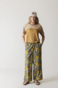 Women's colorblock t-shirt in beige and mustard yellow worn with floral wide-leg pants