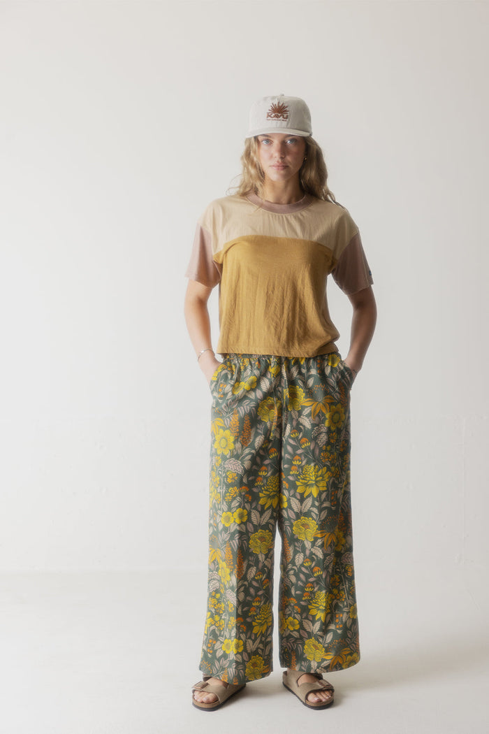 Women's colorblock t-shirt in beige and mustard yellow worn with floral wide-leg pants