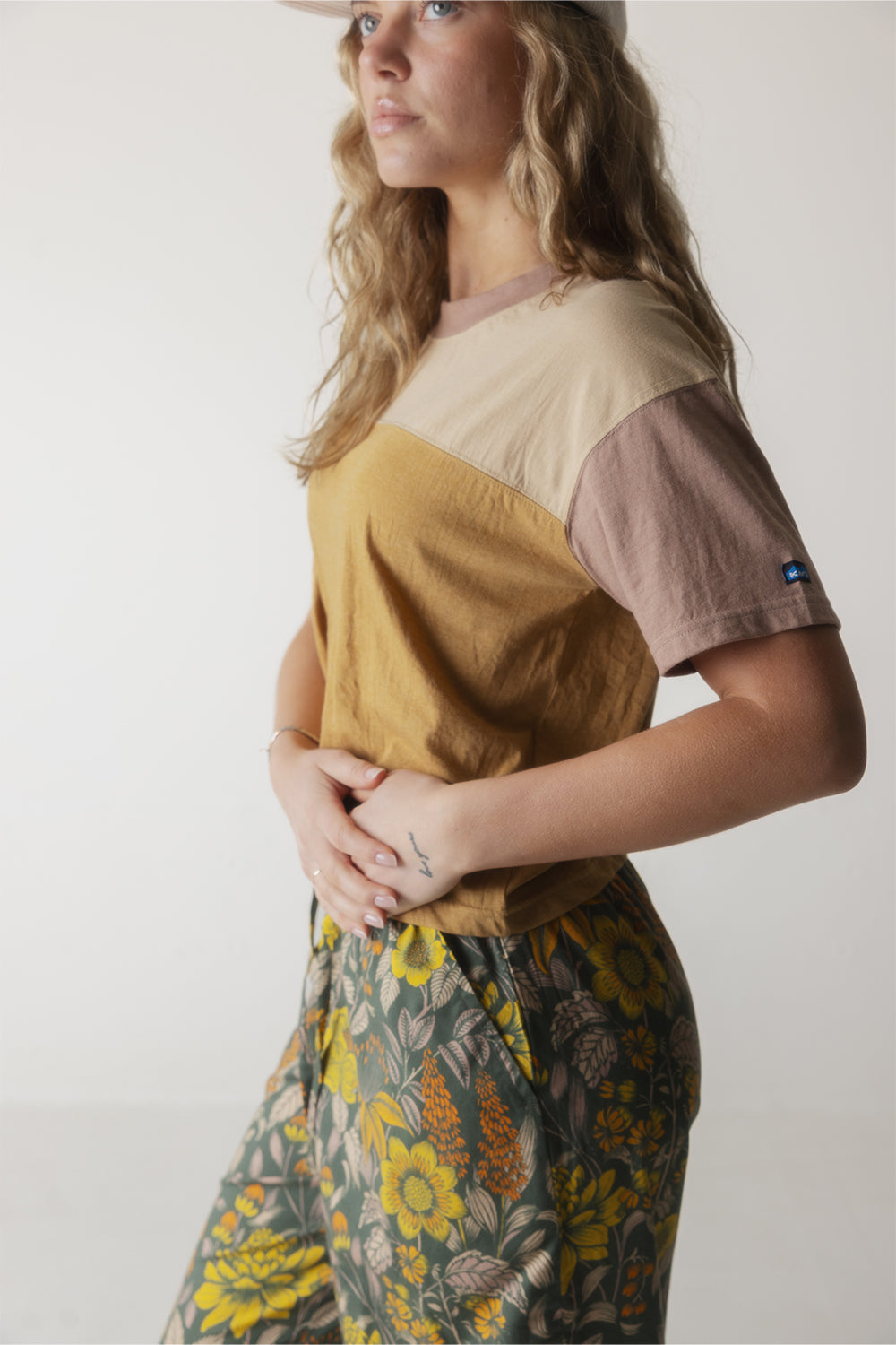 Color block short sleeve shirt with cream, mustard, and mauve sections worn with floral print pants