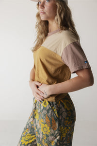 Color block short sleeve shirt with cream, mustard, and mauve sections worn with floral print pants