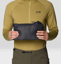 Man holding a packable insulated vest compressed into its own stuff sack, front view