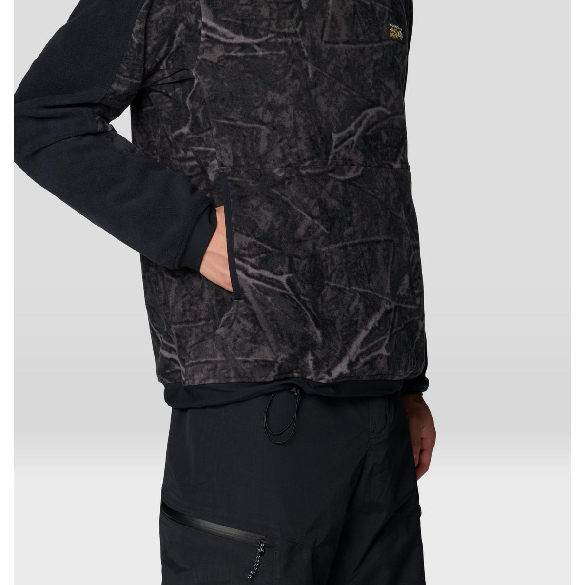 Close-up side view of fleece hoody with tree branch camo print body and solid black sleeves