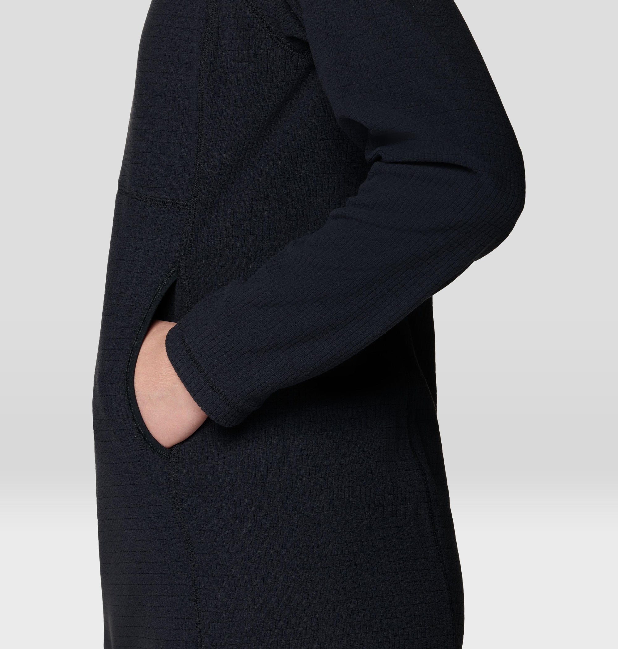 Close-up side detail of black grid-fleece dress showing side pocket with hand inserted